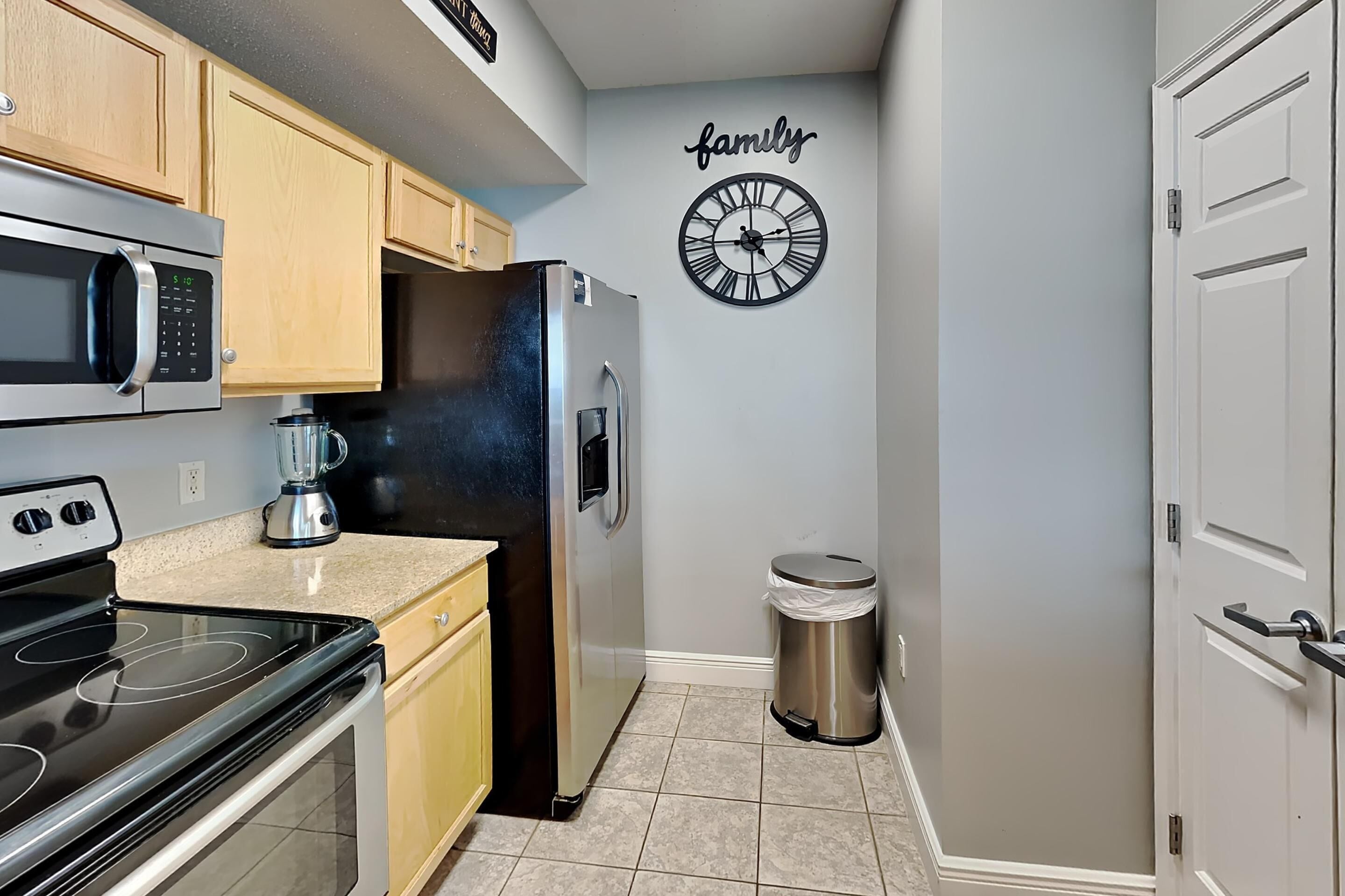 A kitchen with wooden cabinets, a stainless steel refrigerator, a microwave, and a coffee maker.