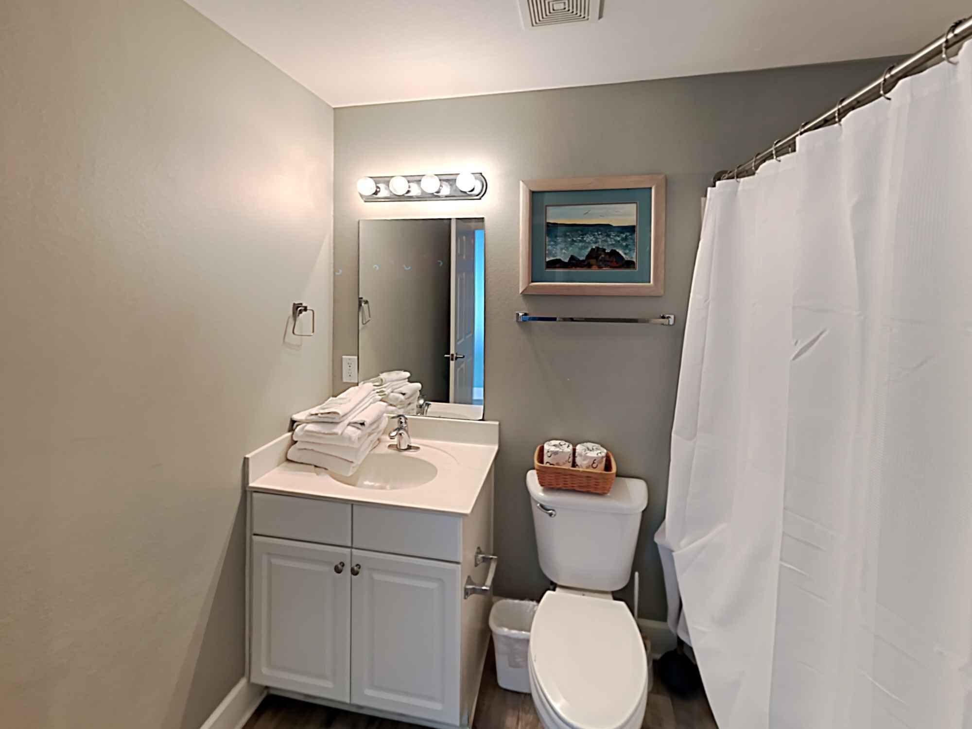 A bathroom with a vanity, sink, mirror, and toilet.