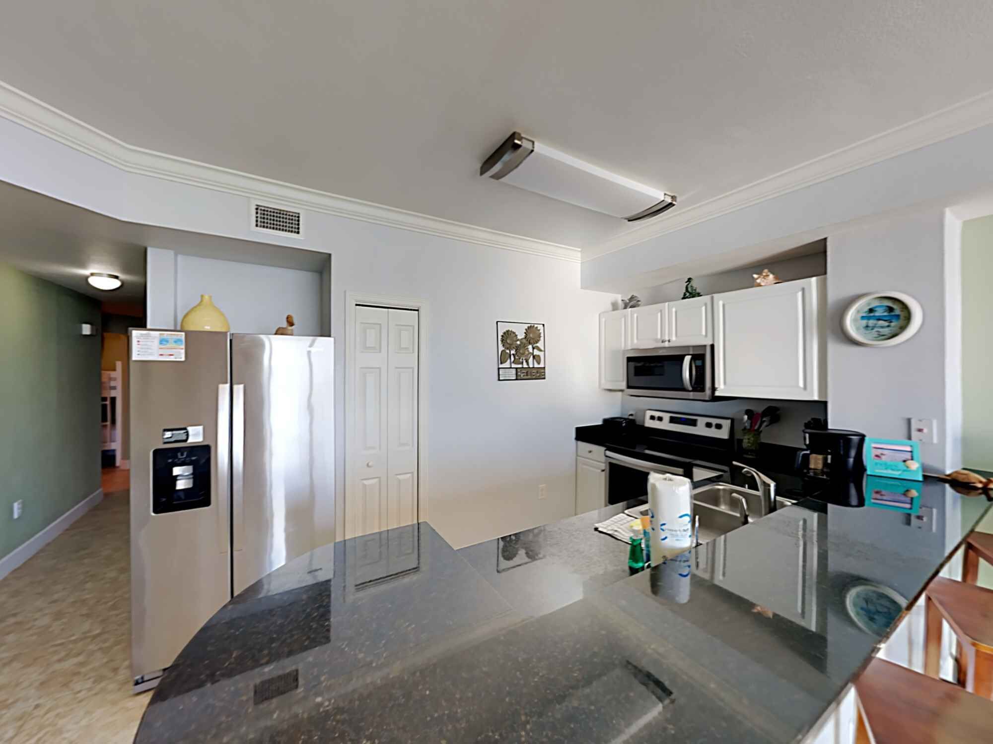 A modern kitchen with a central island, stainless steel appliances, and white cabinetry.