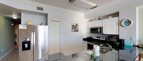A modern kitchen with a central island, stainless steel appliances, and white cabinetry.