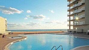 A swimming pool with a view of the ocean, surrounded by a building with balconies. - Tidewater Beach Resort by Resort Collection (Panama City Beach)