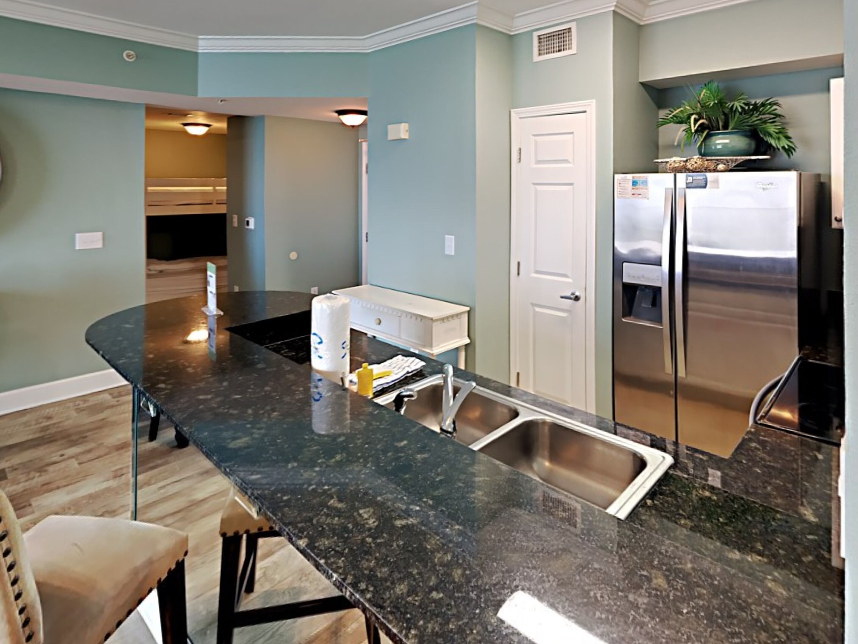 A modern kitchen with a dark granite countertop, stainless steel appliances, and a white door.
