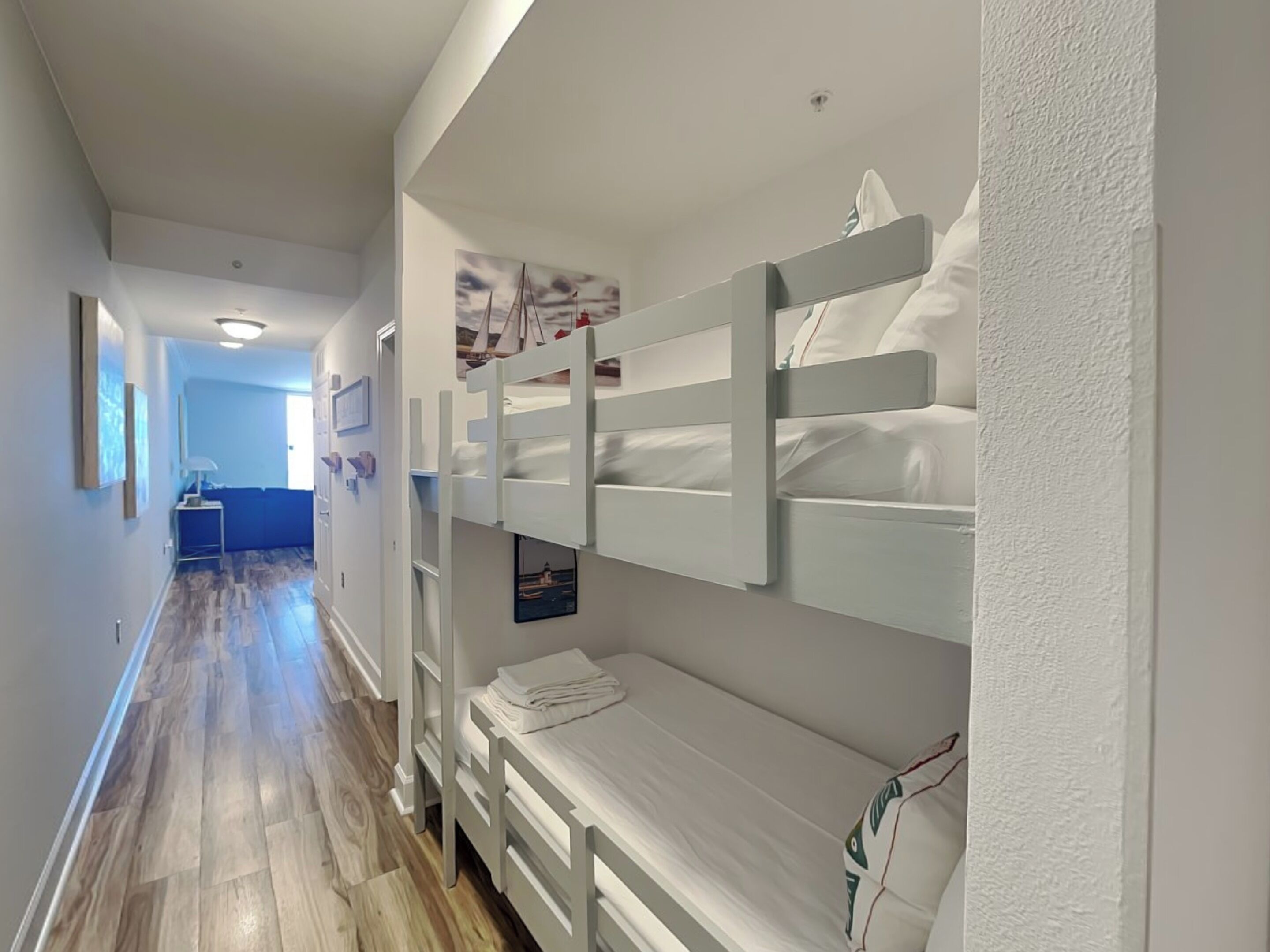 A hotel room with bunk beds, a wooden floor, and a hallway leading to another room.