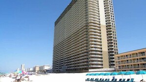 A tall hotel with multiple balconies, located near a beach with sun loungers and umbrellas. - Tidewater Beach Resort by Resort Collection (Panama City Beach)
