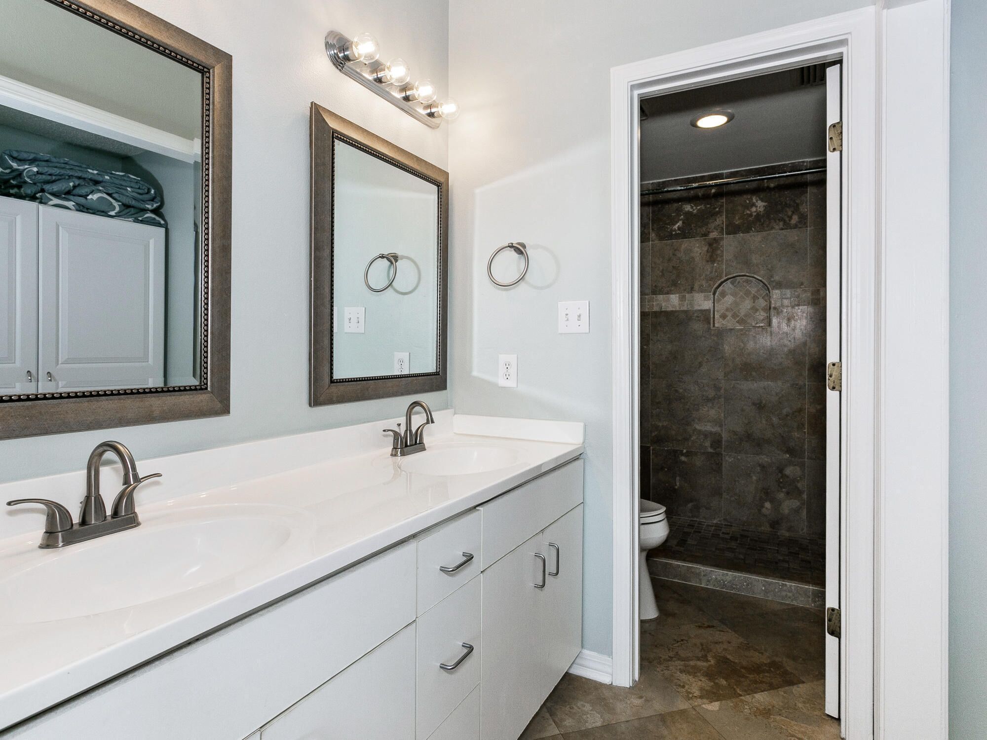 A bathroom with two sinks, a large mirror, and a shower area.