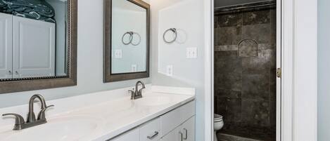 A bathroom with two sinks, a large mirror, and a shower area.