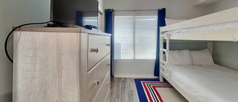 Una habitación con una cama litera, un aparador de madera y una ventana con persianas.
