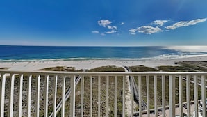 A beach view with a railing in the foreground, a clear sky, and the ocean in the background. - Tidewater Orange Beach by Southern Vacation Rentals (Orange Beach)