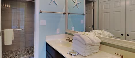 A bathroom with a large mirror, a sink, and a towel rack.