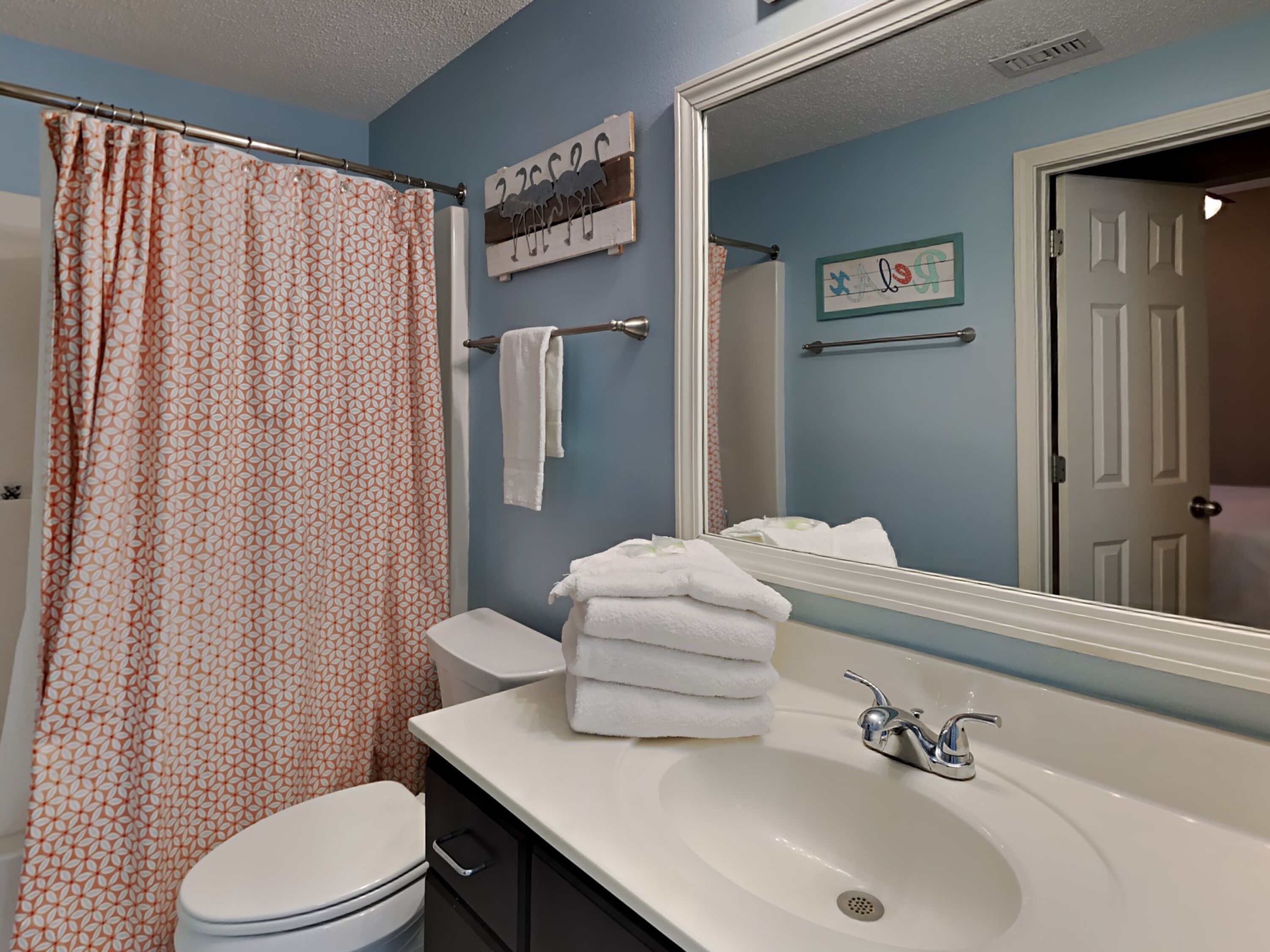 A bathroom with a toilet, sink, and shower curtain.