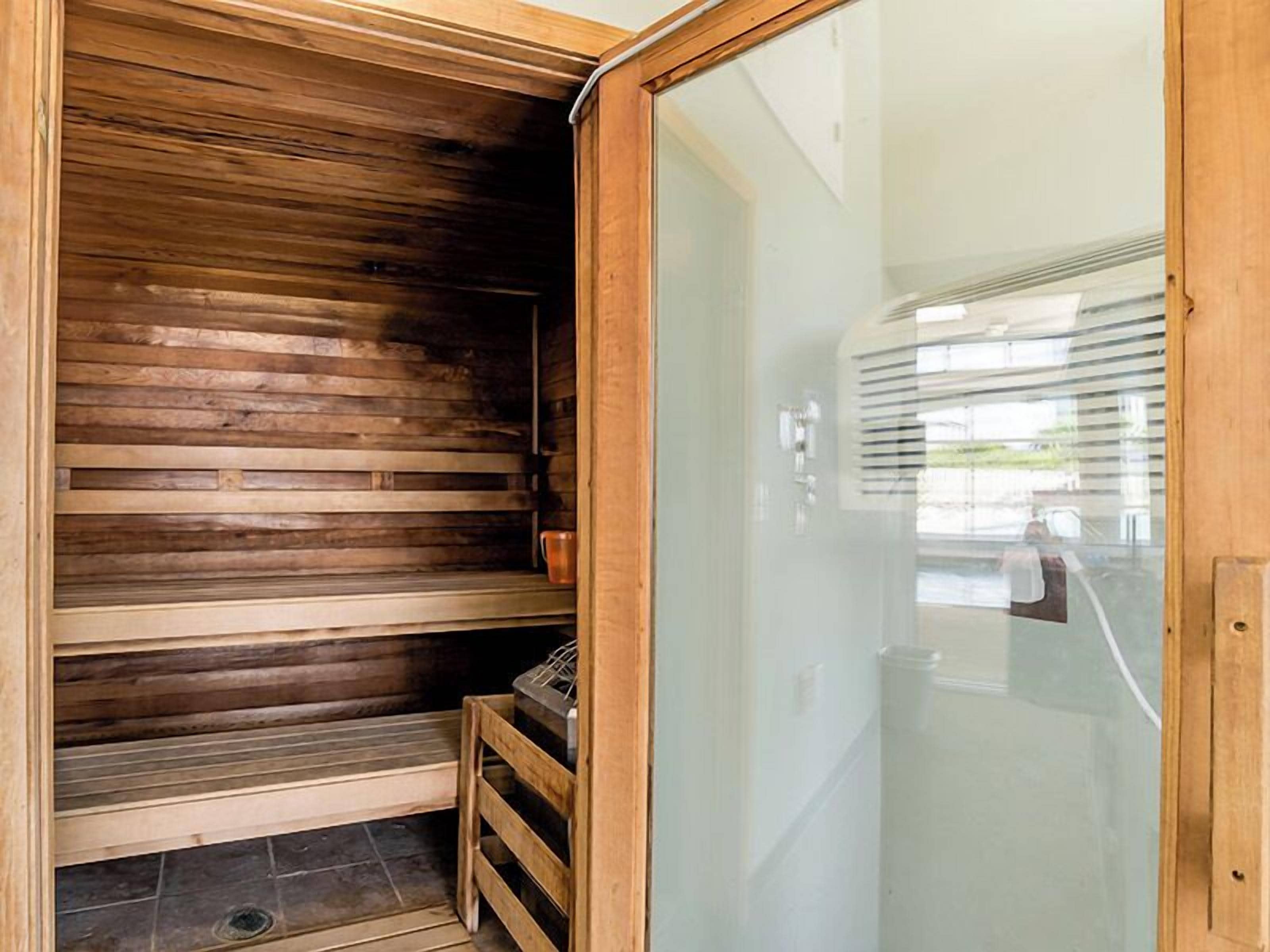 A sauna with wooden benches and a glass door.