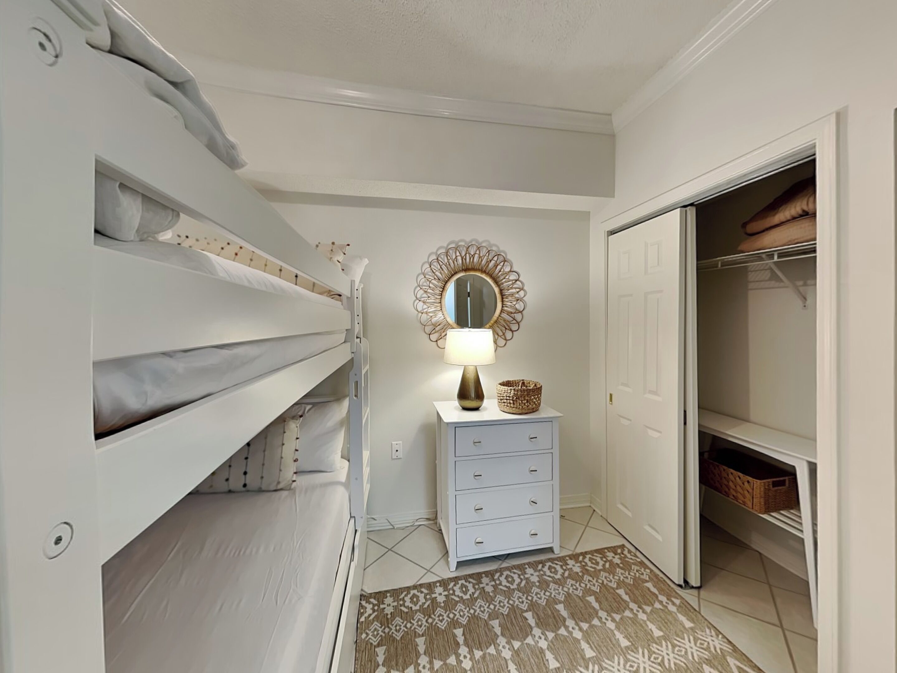 Een slaapkamer met stapelbedden, een dressoir, een spiegel en een kledingkast.