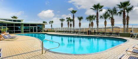 A pool area with lounge chairs and palm trees.