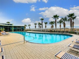 A pool area with lounge chairs and palm trees.