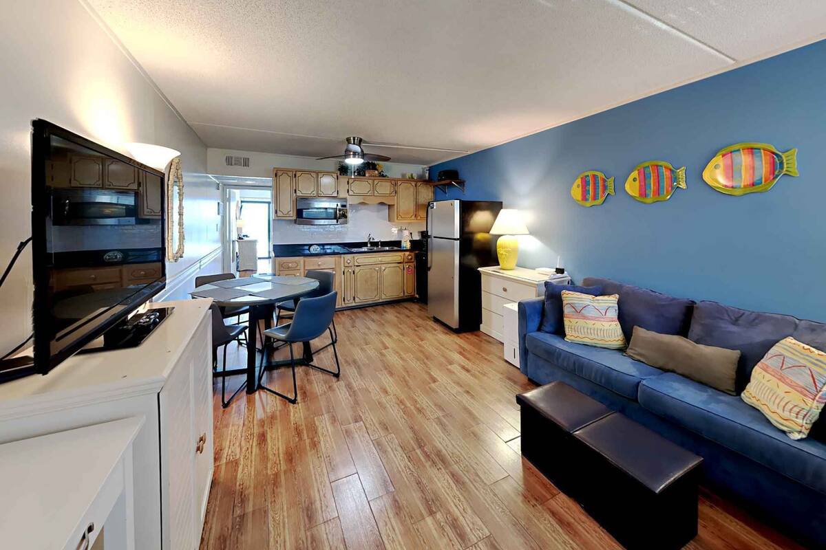 A compact living space with a kitchenette, a dining area, and a seating area with a sofa and a bench.