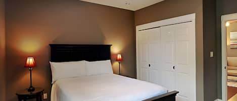 A bedroom with a bed, two bedside lamps, a ceiling fan, and a wardrobe.