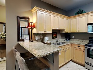 A kitchen with granite countertops, wooden cabinets, a built-in oven, and a coffee maker. - Topsail Village by Southern Vacation Rentals (Santa Rosa Beach)