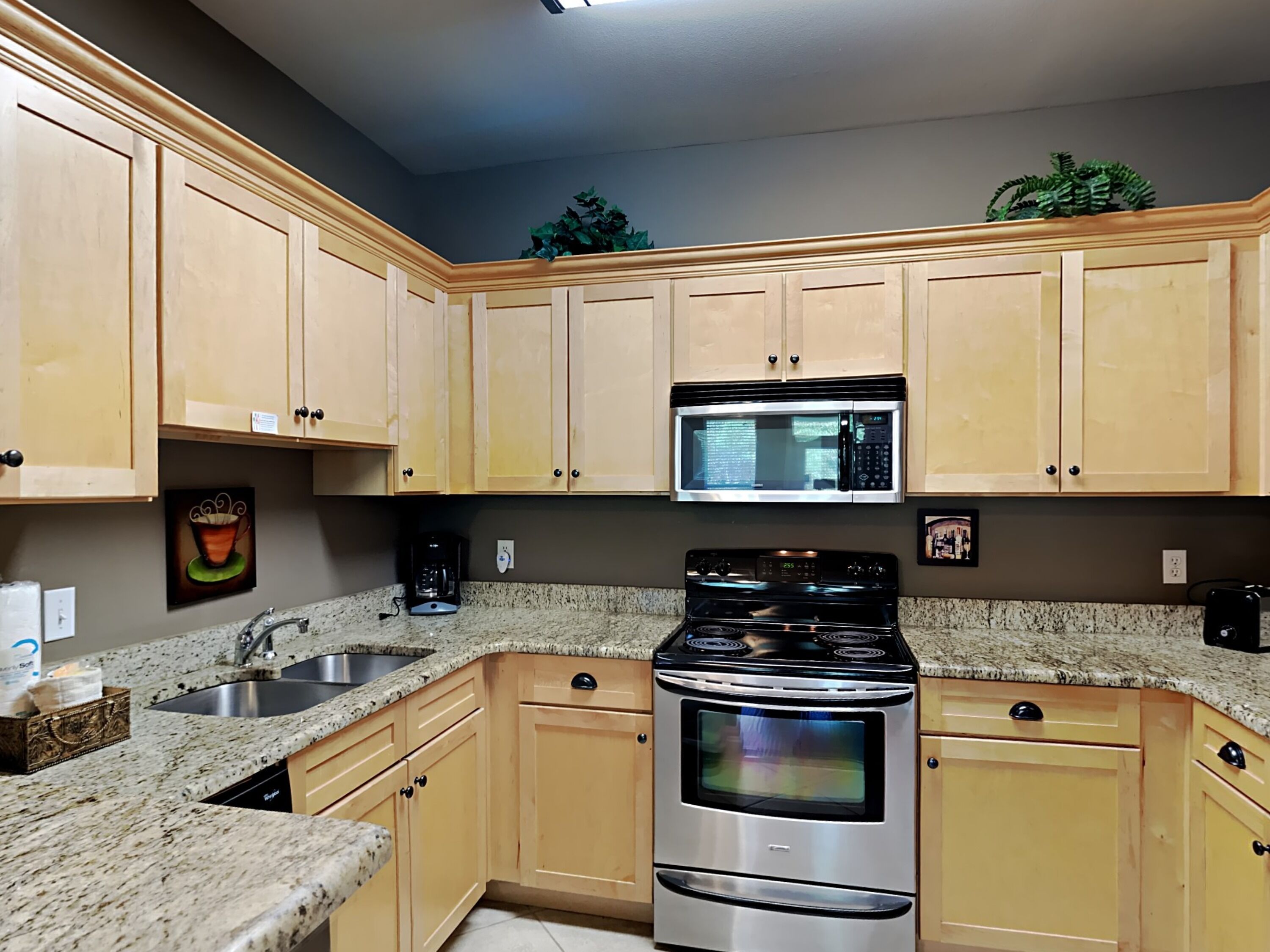A kitchen with wooden cabinets, a stainless steel stove, a microwave, and granite countertops.