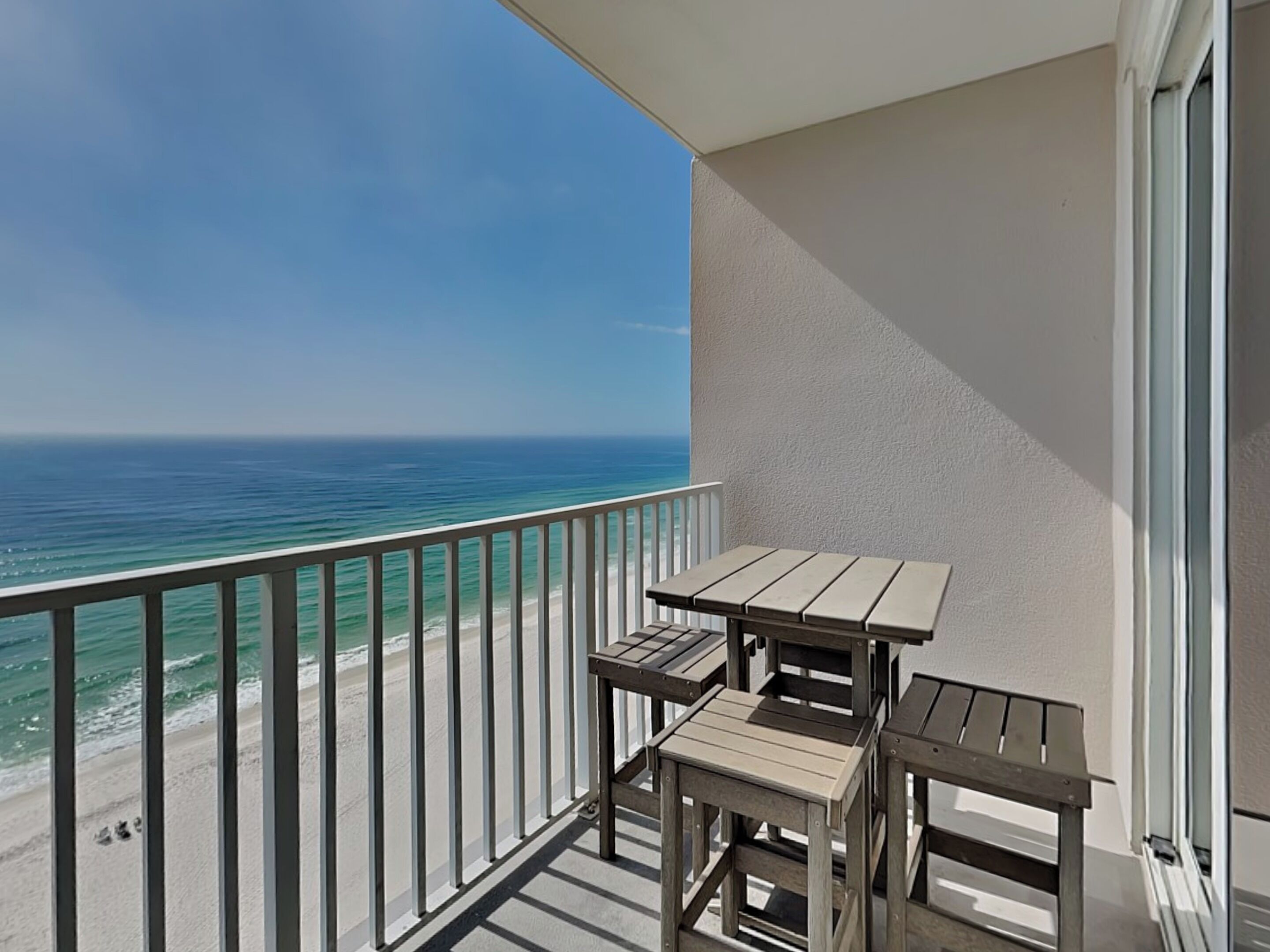 A balcony with a view of the ocean and a small table.