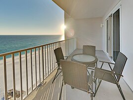Un balcon avec vue sur l’océan, une table ronde et quatre chaises en osier.