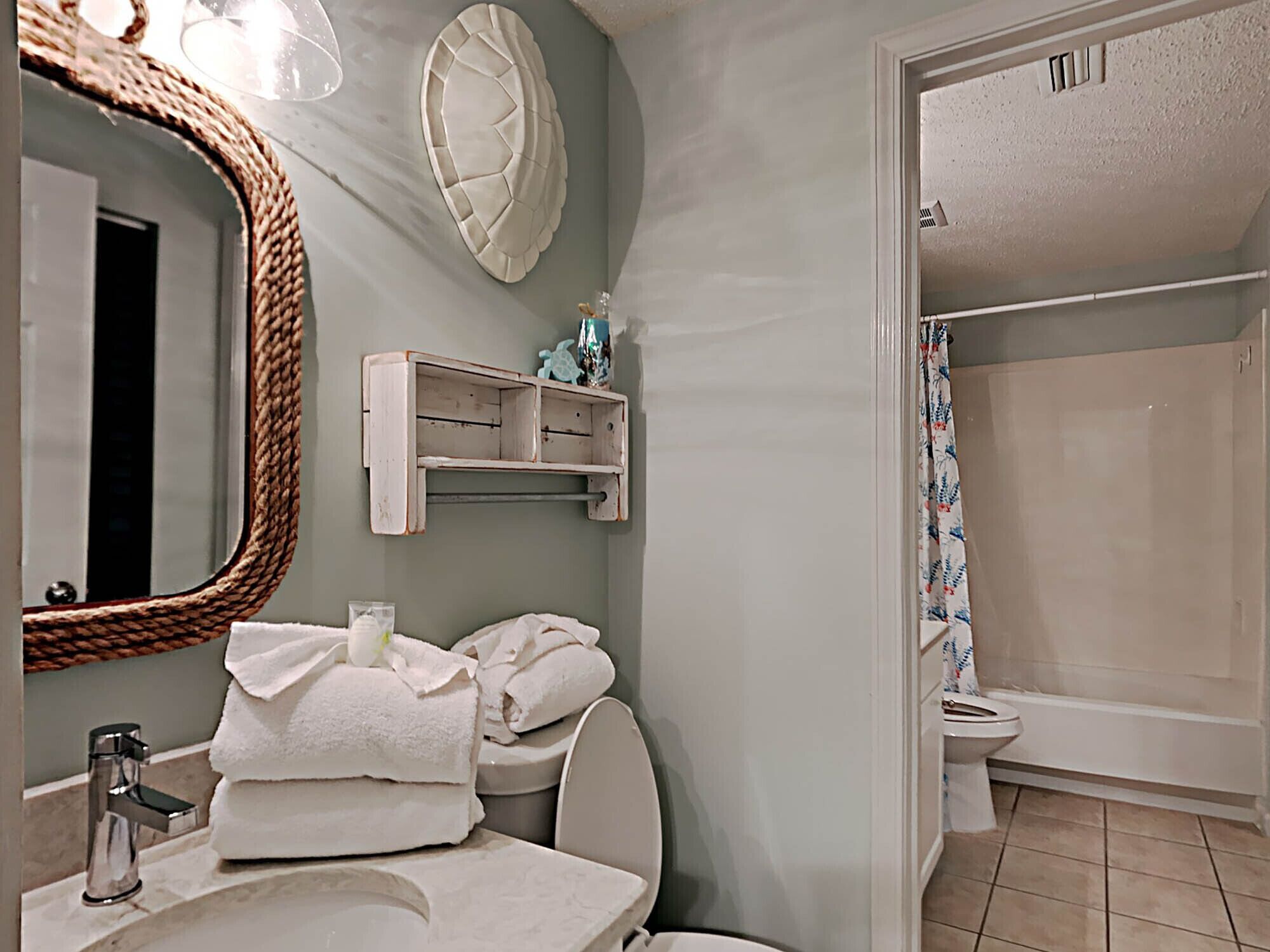 A bathroom with a mirror, sink, toilet, and shower.