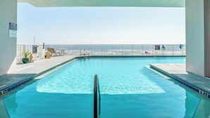 Une piscine à l’eau d’un bleu cristallin, une clôture blanche et une vue sur l’océan.