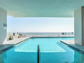 Une piscine à l’eau d’un bleu cristallin, une clôture blanche et une vue sur l’océan.
