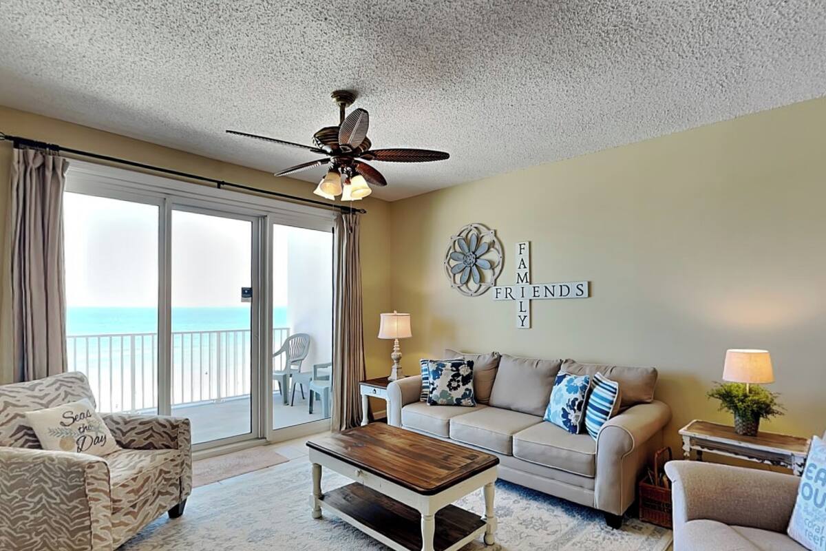 A living room with a view of the ocean, a ceiling fan, and a sign that reads "FAMILY FRIENDS".