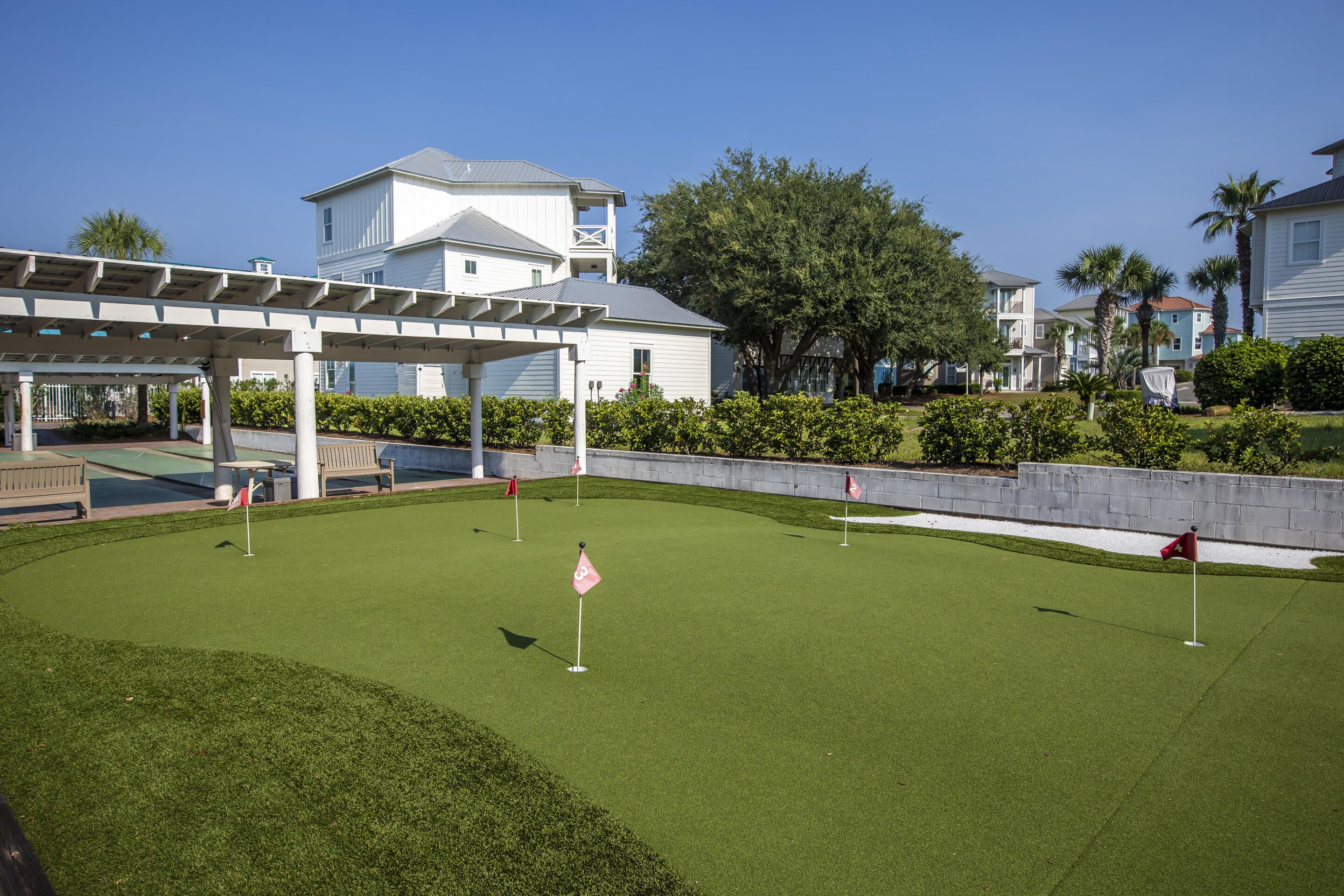 A golf course with a pavilion, a white building, and a well-maintained lawn.