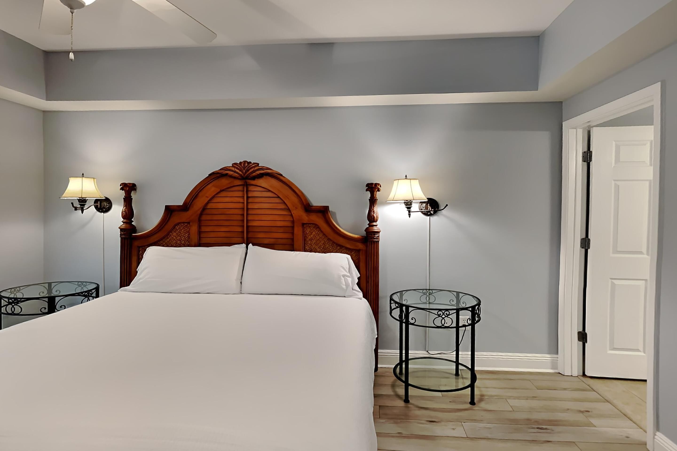 Een slaapkamer met een groot bed, twee wandlampen en een deur.