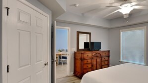 Quarto com cama, penteadeira e ventilador de teto.