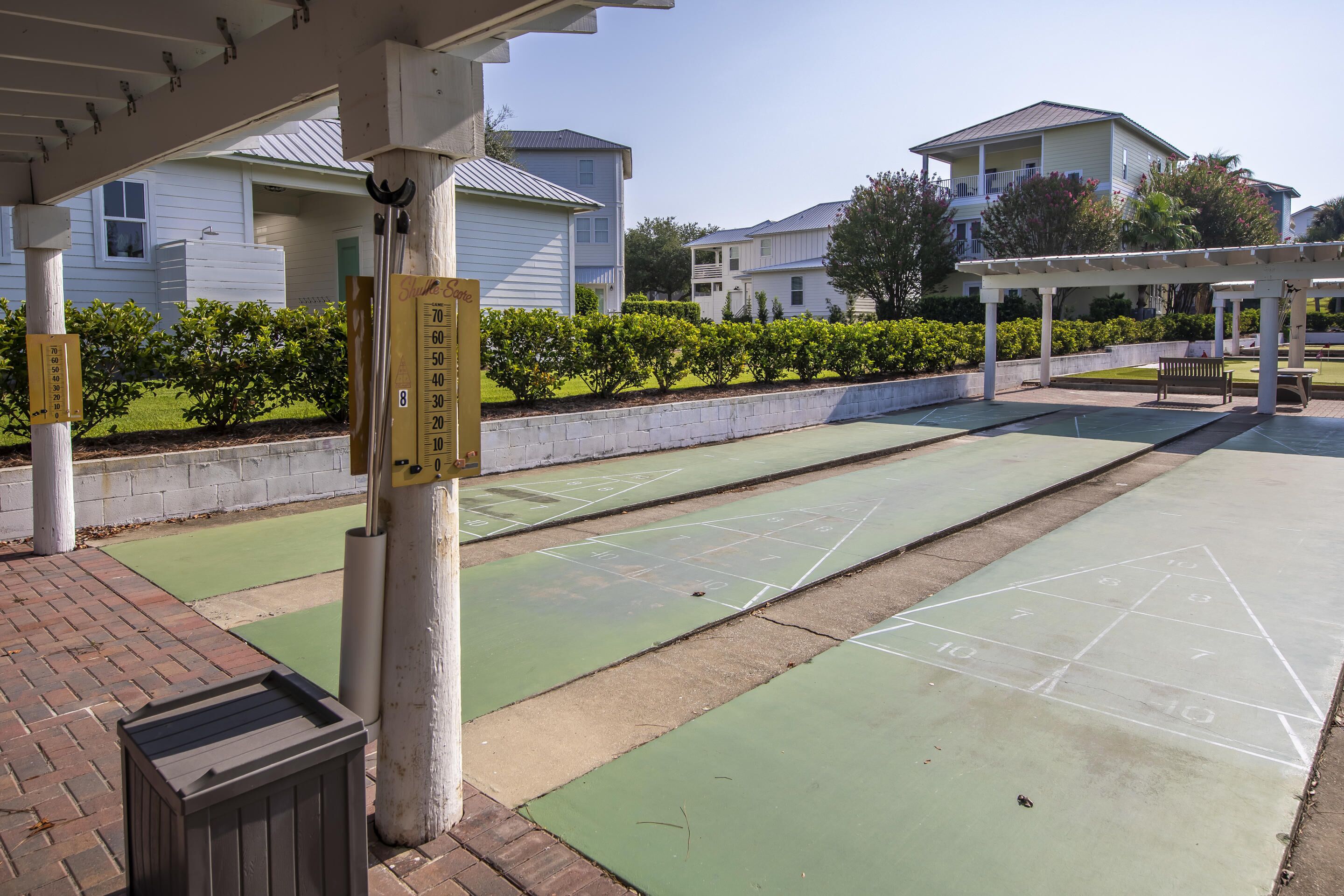 Ein Innenhof mit Shuffleboard-Tischen, einer Bank und einer Pergola.
