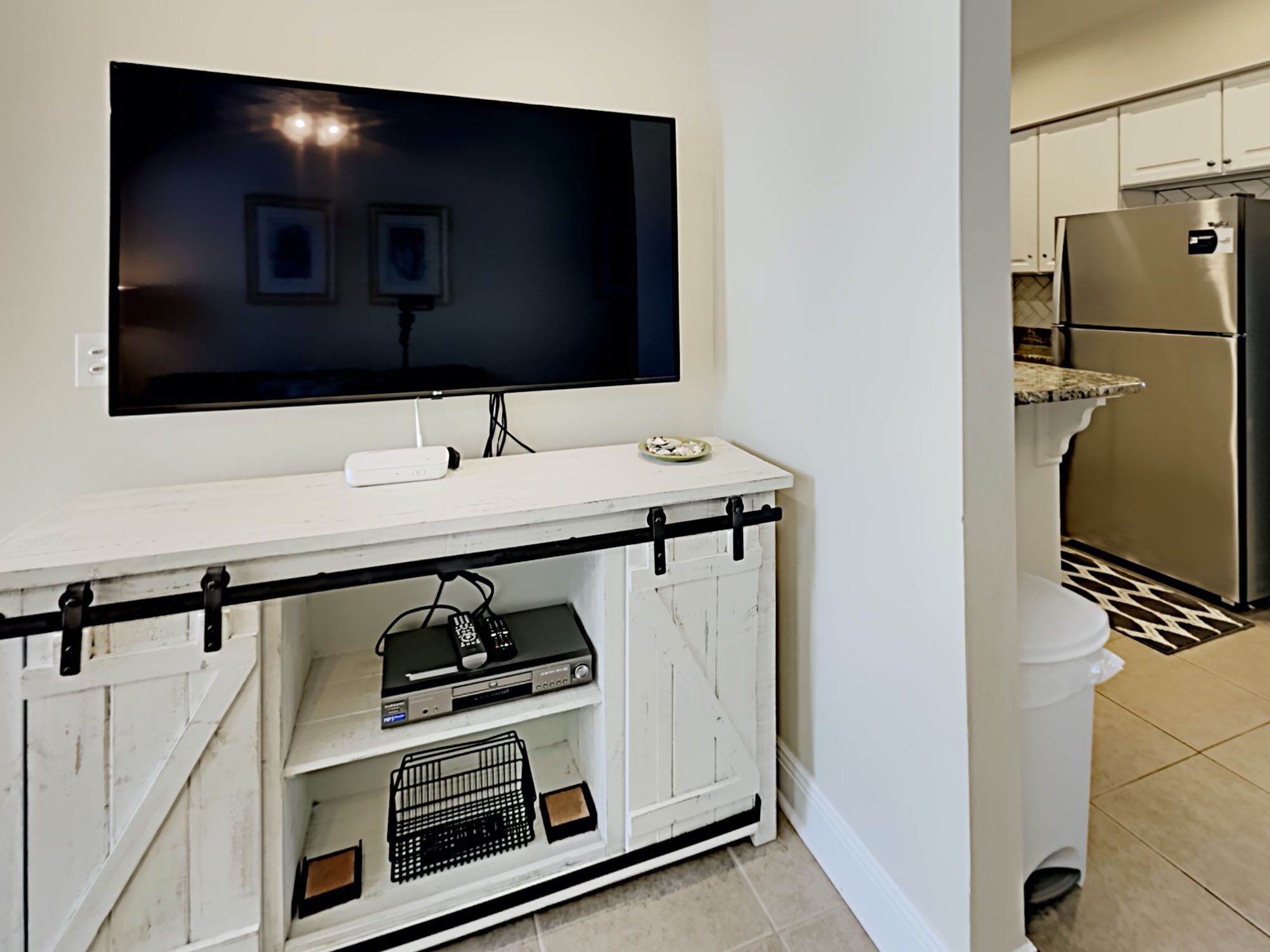 A modern kitchen with a built-in refrigerator, a white countertop, and a mounted flat-screen TV.