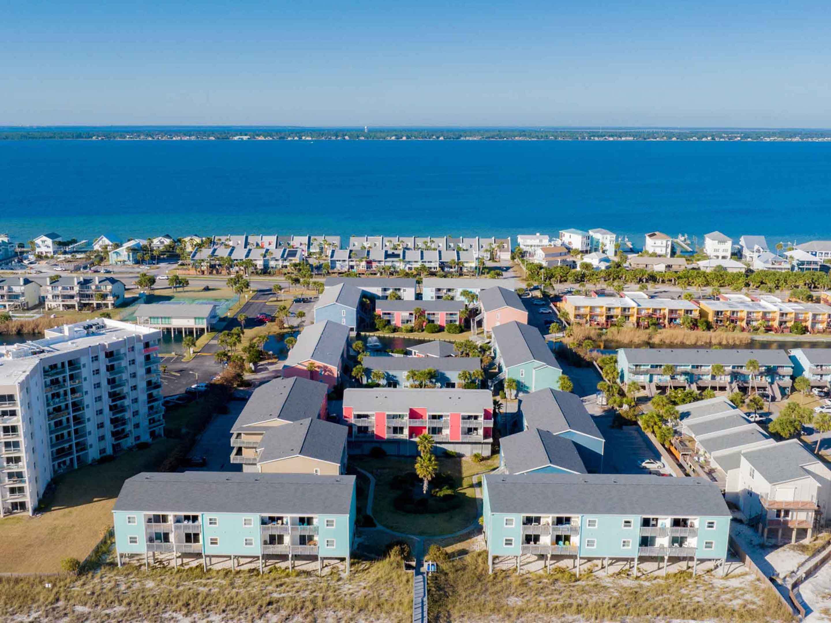 A coastal resort with multiple buildings, including a prominent multi-story structure with balconies, situated near a body of water.