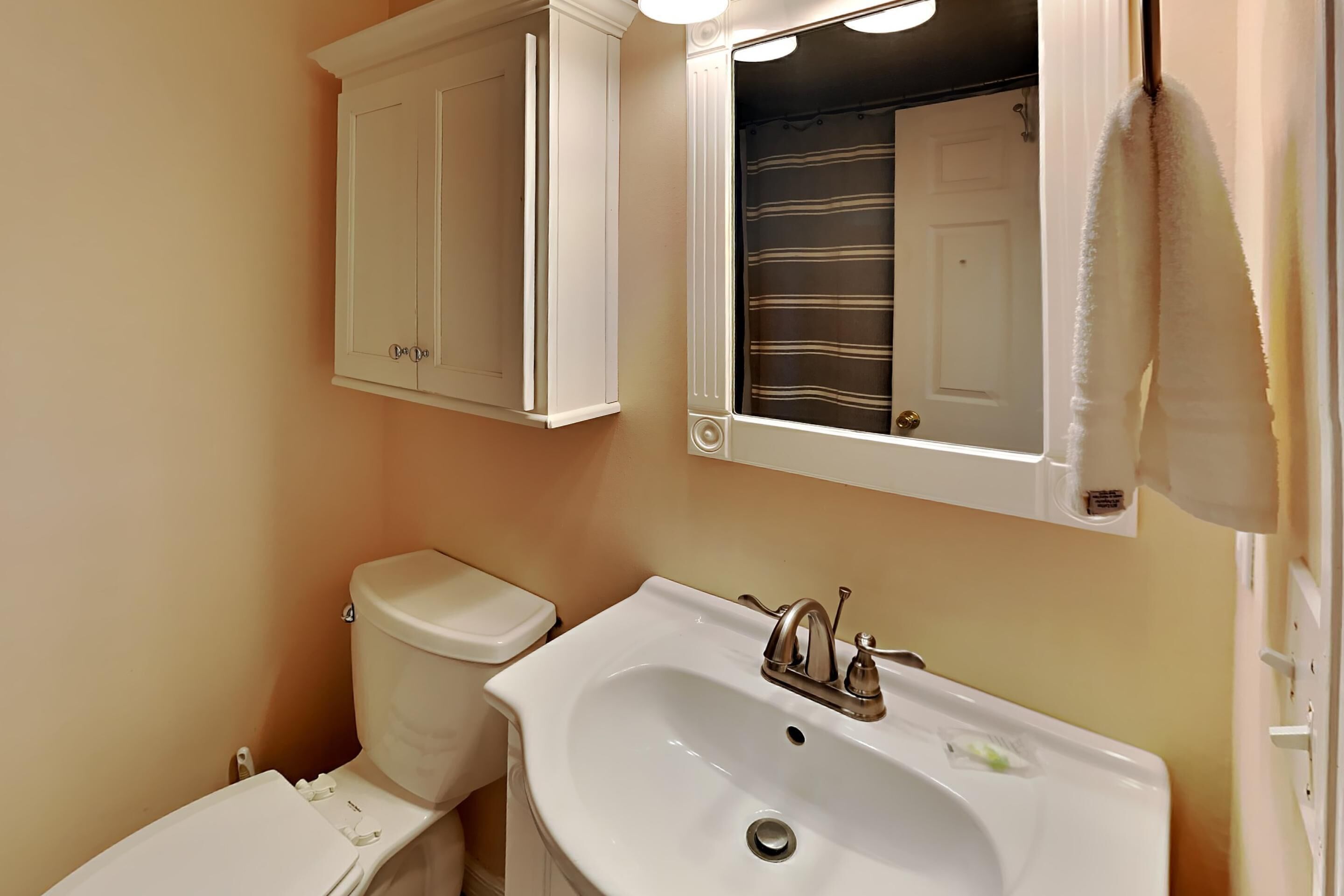 A bathroom with a toilet, a sink, and a mirror.