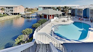 Un hotel con piscina, un molo e vista sull'acqua.