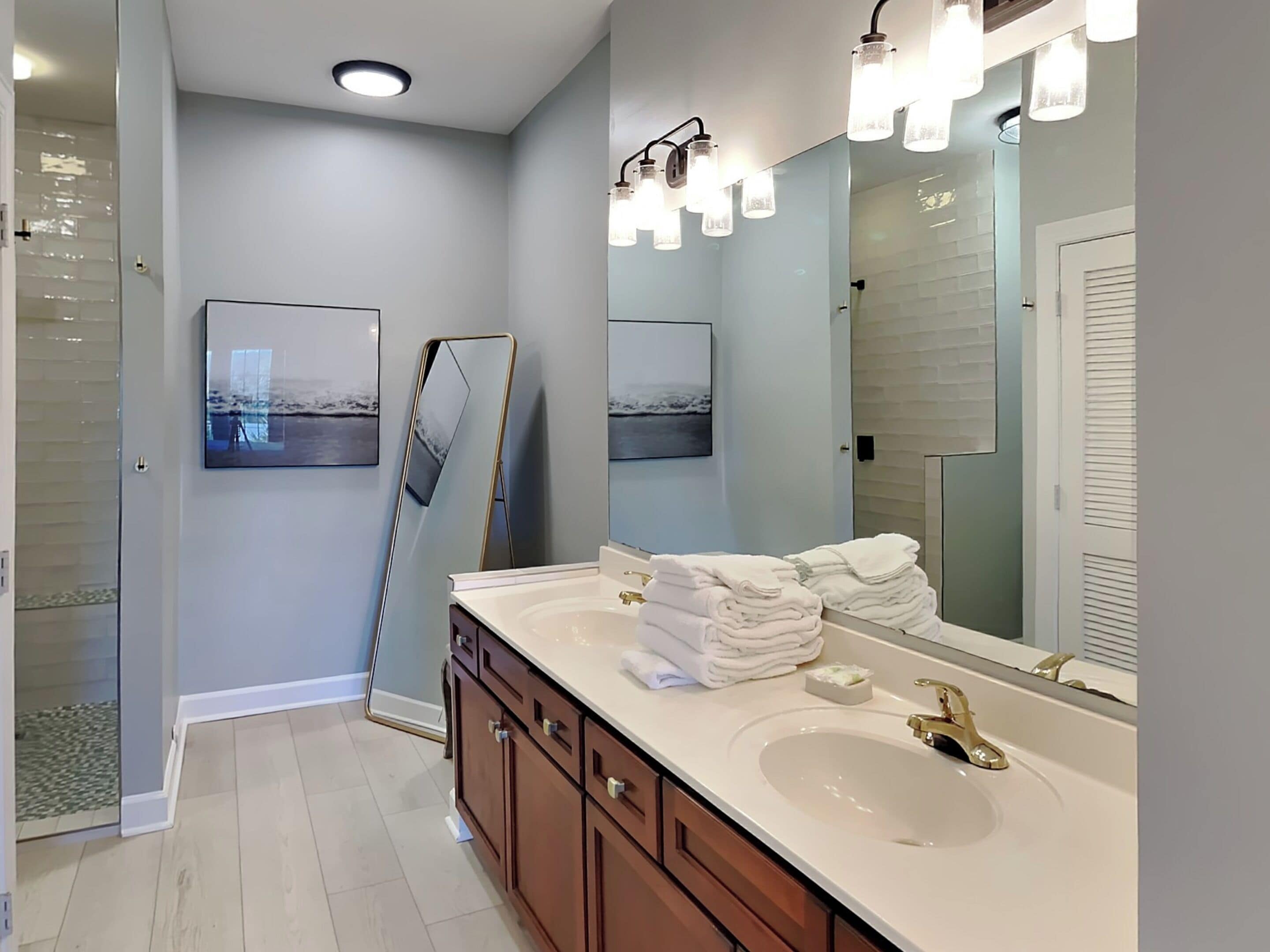 A modern bathroom with dual sinks, a large mirror, and a glass shower enclosure.