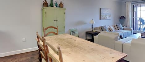 Un comedor con una mesa y sillas de madera, un armario verde con objetos decorativos, un sofá y una lámpara.