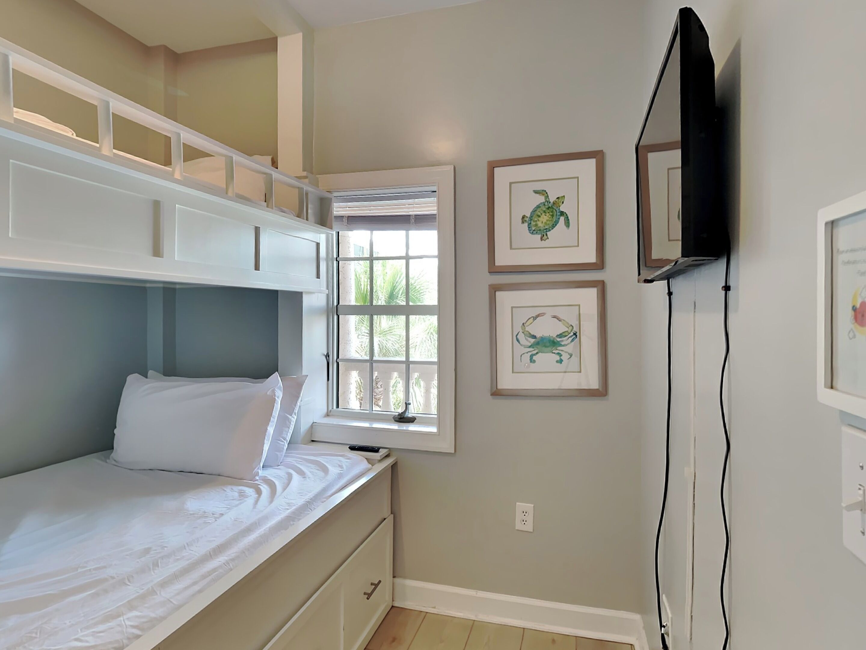 Une chambre avec un lit superposé, une fenêtre donnant sur un beau paysage et deux tableaux encadrés accrochés au mur.