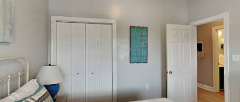 Un dormitorio con cama, mesita de noche, lámpara, armario y una pared con una cita motivacional.