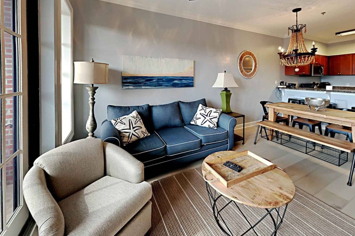 A living room with a sofa, armchair, coffee table, and a painting on the wall.