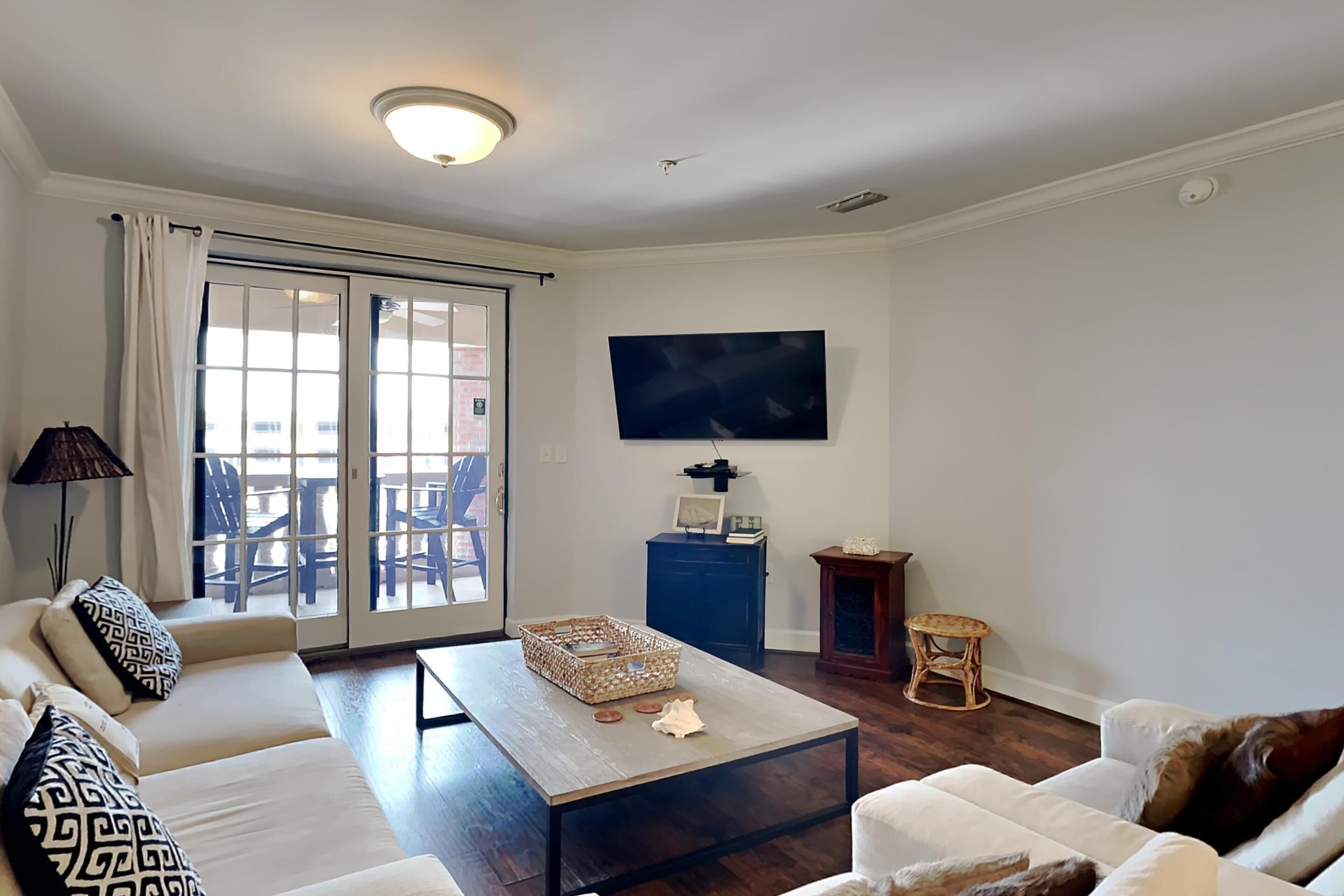 A living room with a sofa, coffee table, and a television on the wall.