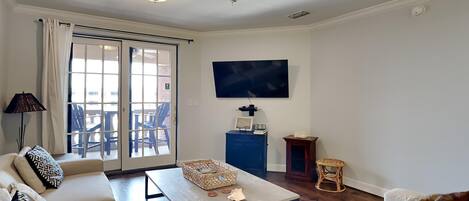 A living room with a sofa, coffee table, and a television on the wall.