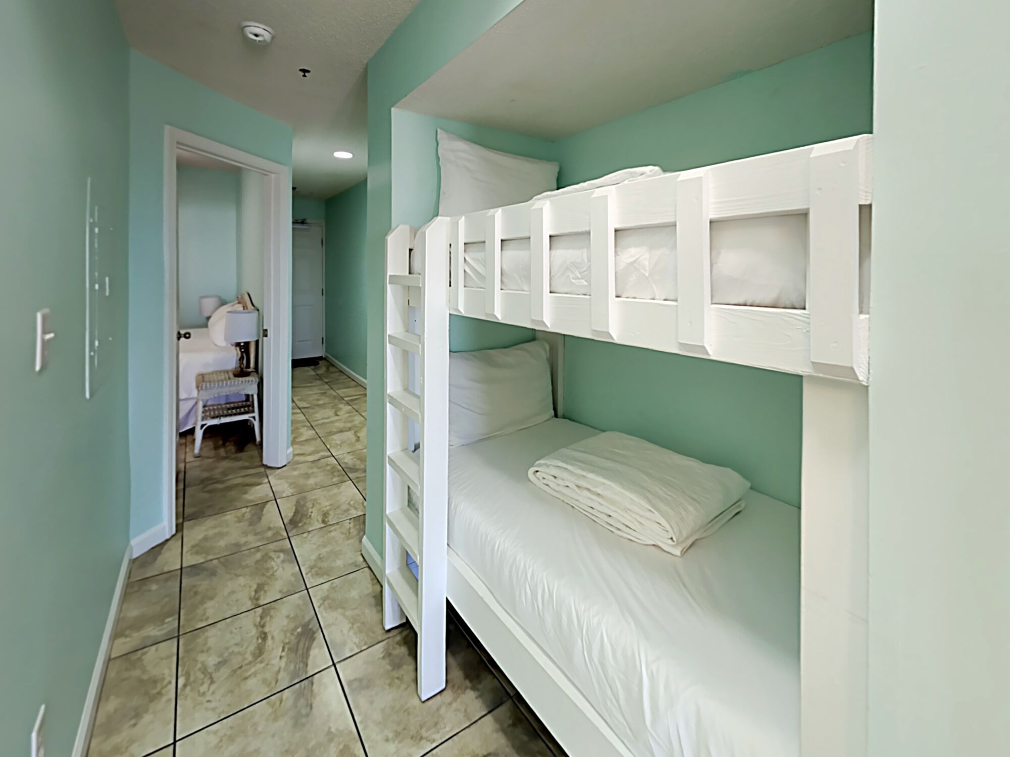 A room with bunk beds, a desk, and a chair.