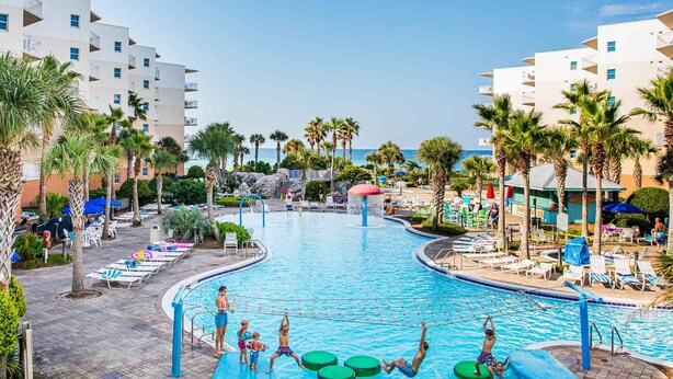 A resort pool area with palm trees, lounge chairs, and a view of the ocean. - Waterscape by Southern Vacation Rentals (Fort Walton Beach)