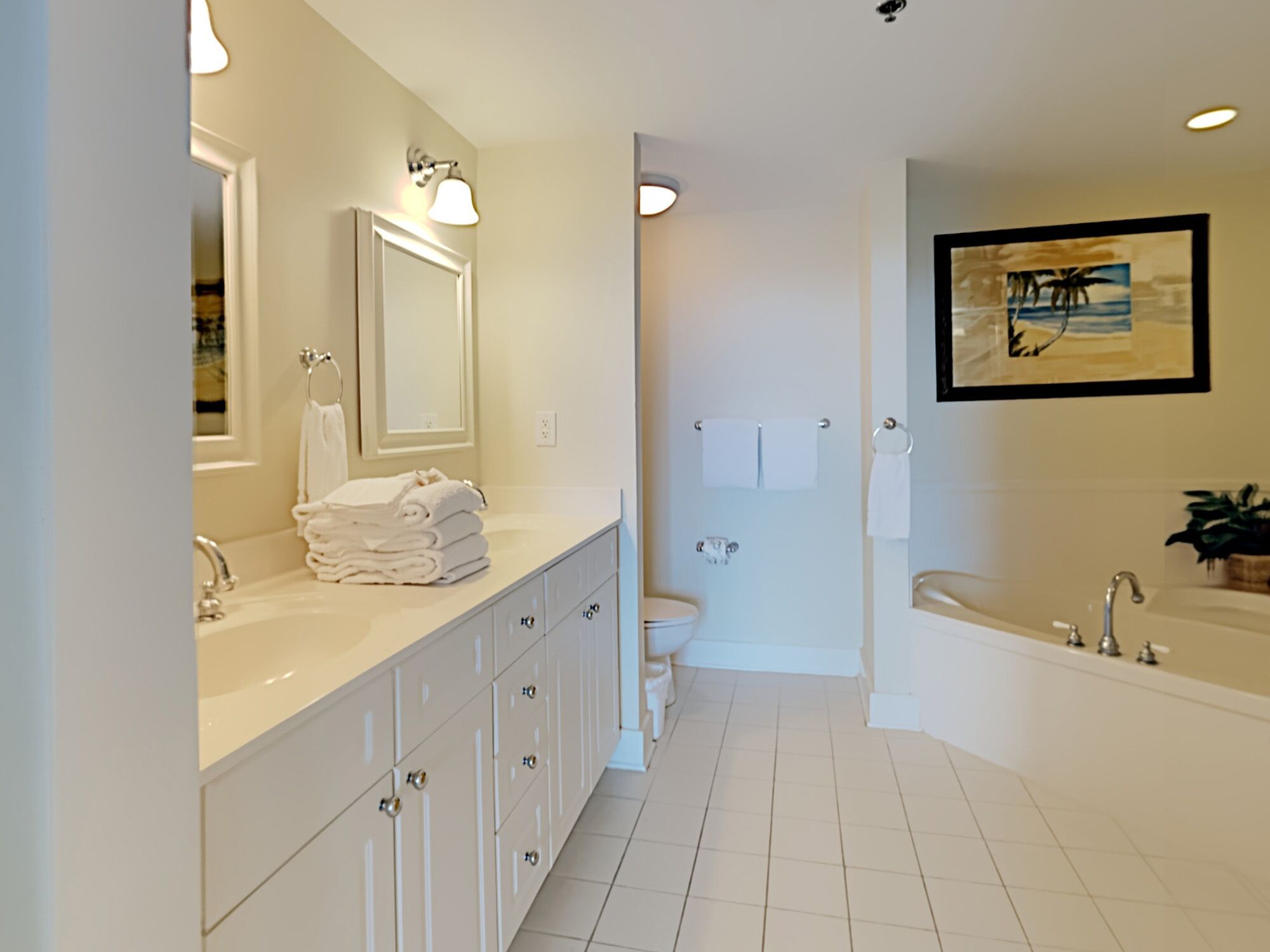 A modern bathroom with a large vanity, a bathtub, and a toilet.