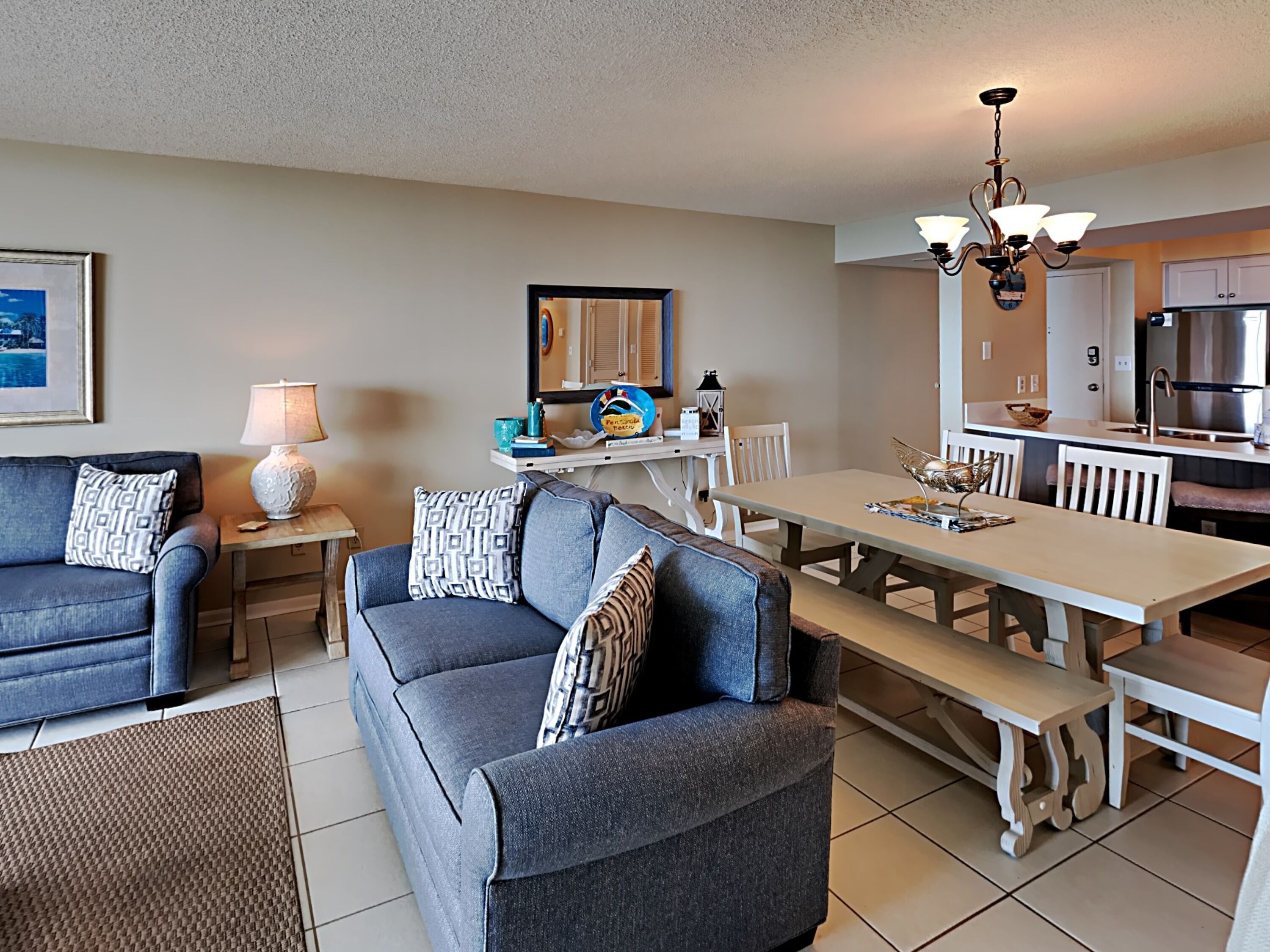A modern living room with a sofa, a dining table, and a kitchen area.