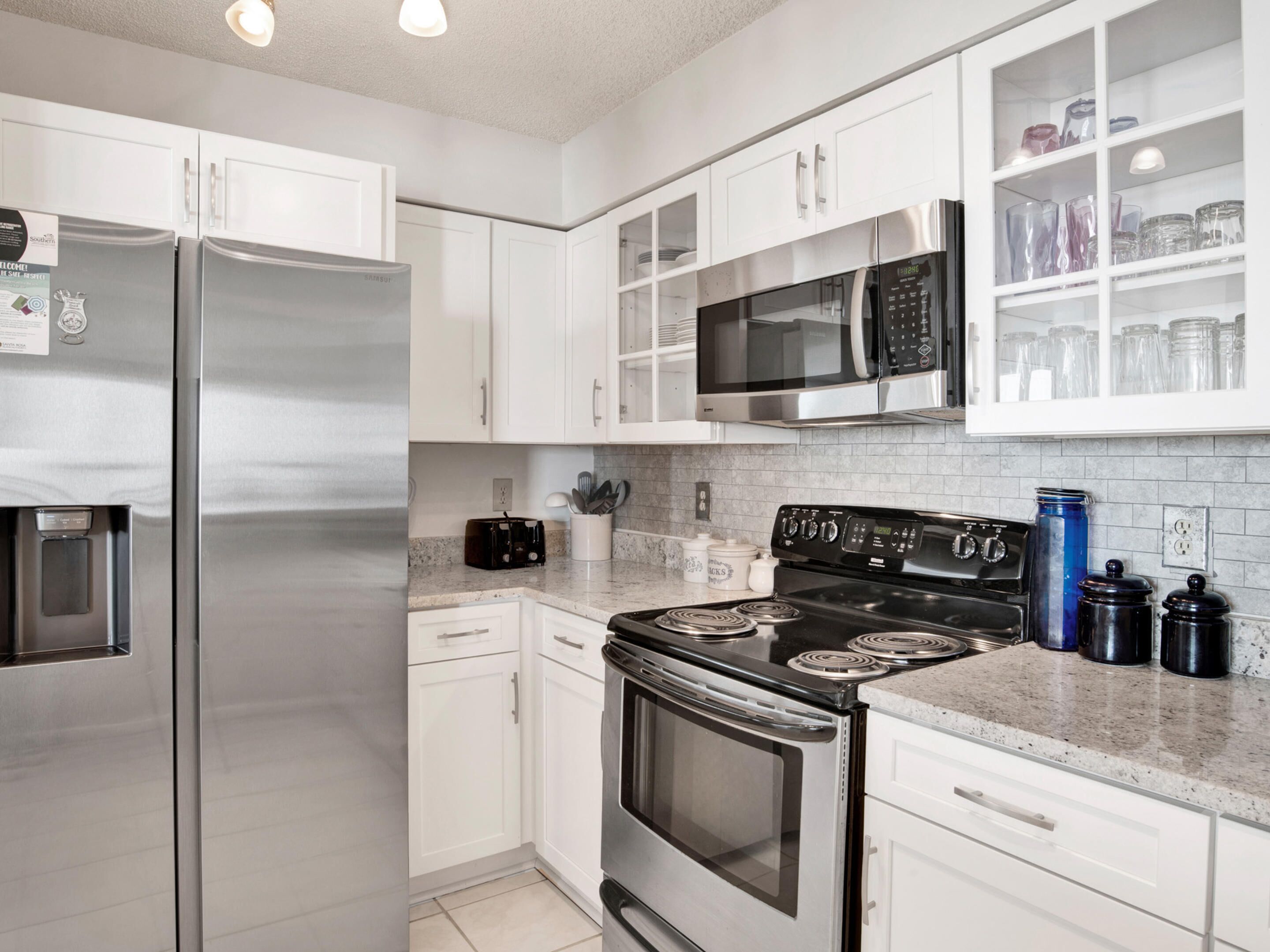 A modern kitchen with stainless steel appliances, white cabinetry, and a microwave above the stove.