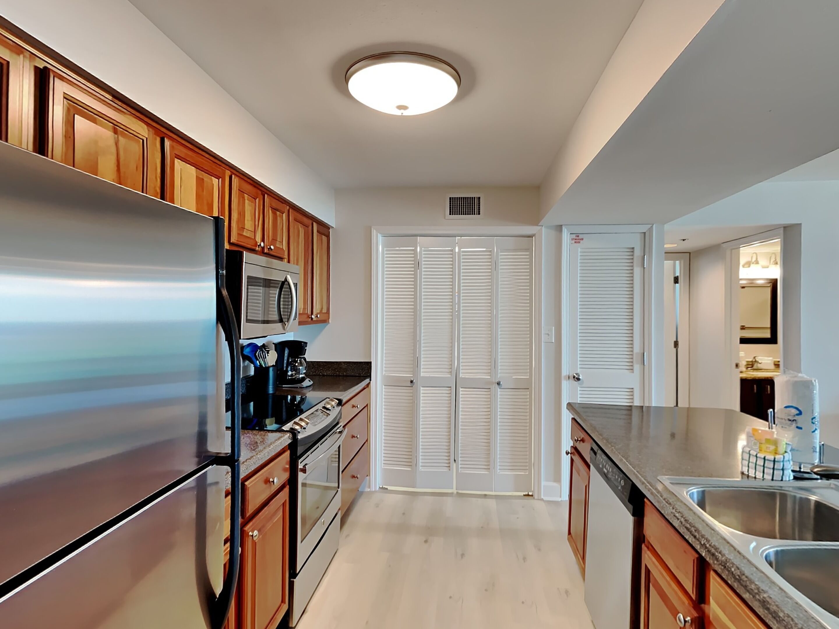 Une cuisine moderne avec des meubles en bois, des appareils en acier inoxydable et un placard à deux portes.