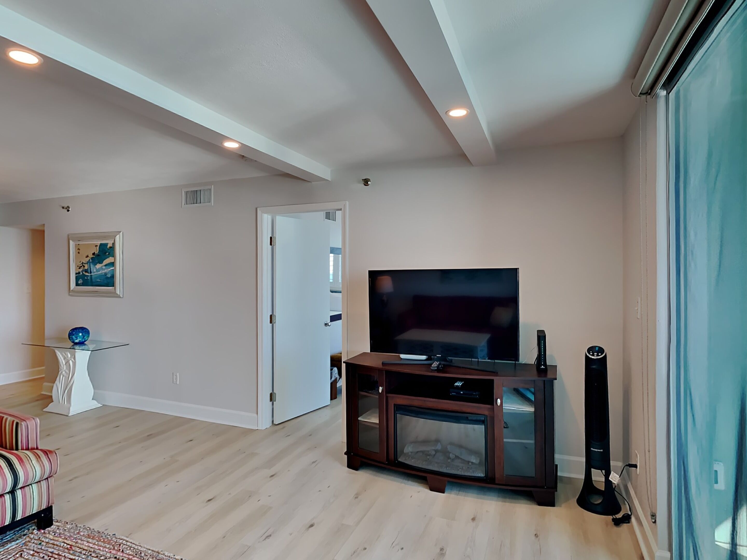 A living room with a flat-screen TV, a fireplace, and a glass coffee table.